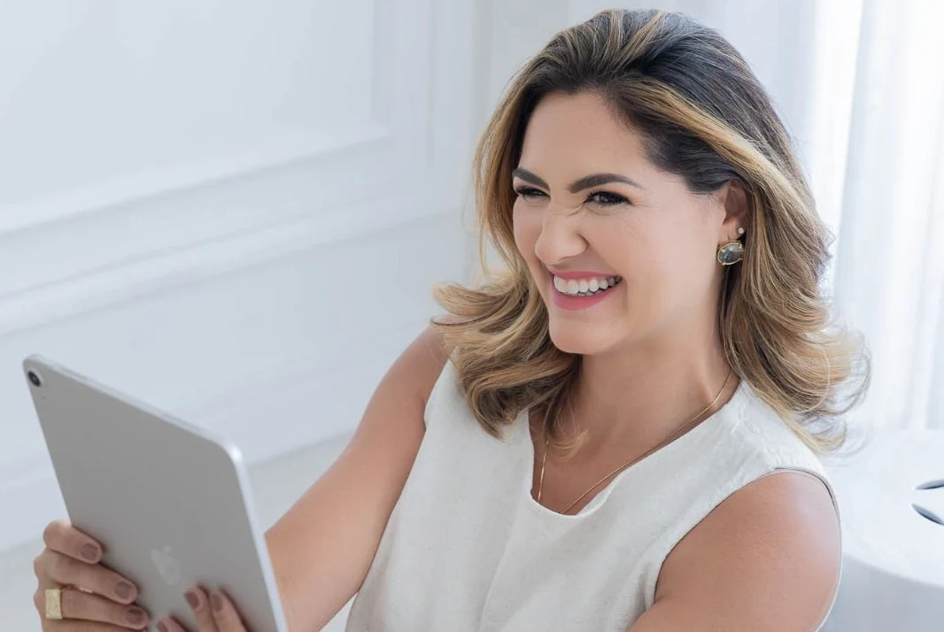 Renata Fantinati sorrindo, com um tablet nas mãos.