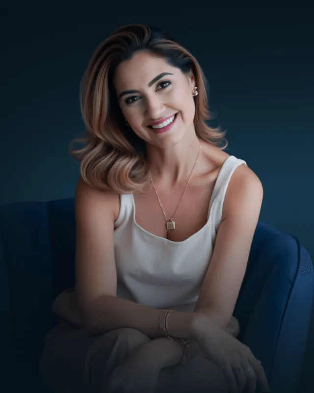 Renata Fantinati sentada numa poltrona azul, sorrindo.